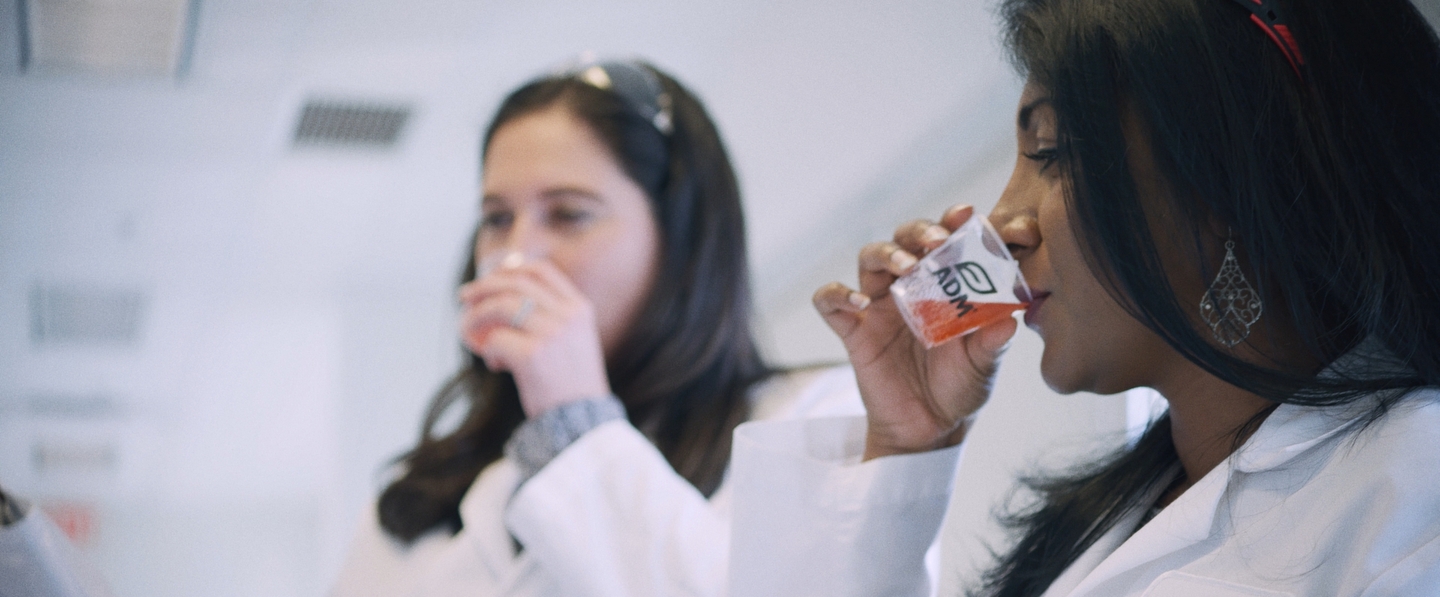 Scientist in a white coat tasting flavor in a lab